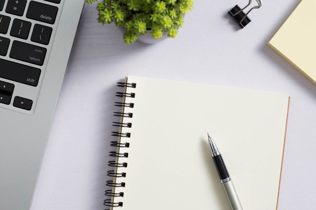 top view of a white desk with laptop and supplies